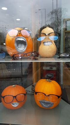 two pumpkins with different faces and glasses on display in a store window, one has an emoticive expression