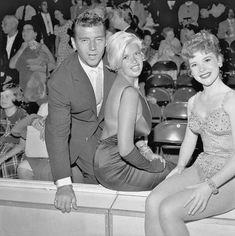 two women and a man sitting on a bench in front of an audience