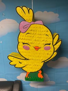 a paper cut out of a yellow bird with pink bow on it's head