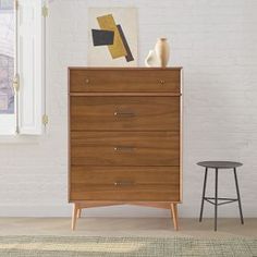 a wooden dresser sitting next to a window in a room with a rug on the floor