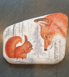 a painted rock with an image of a fox and a squirrel on it