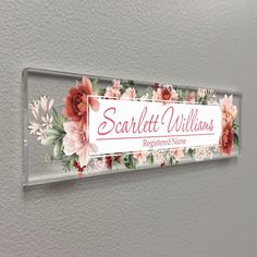 a sign that is hanging on the side of a wall with flowers and leaves painted on it