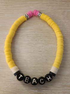 a yellow and black beaded bracelet with the word teach written in silver letters on it