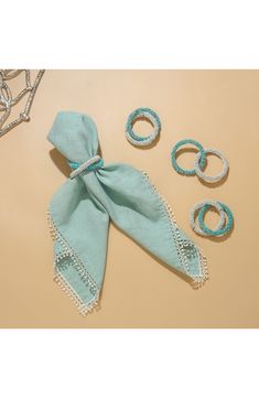 three pieces of blue fabric with white lace on them and two rings in the middle