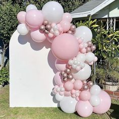 a bunch of balloons that are on the ground in front of a wall and bushes