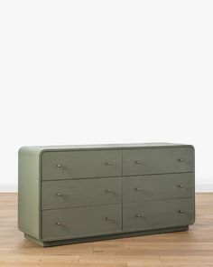 a green dresser sitting on top of a hard wood floor next to a white wall