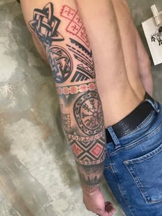 a man's arm with tattoos on it and his hand holding the other arm