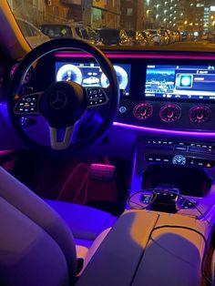 the interior of a modern car with purple lighting and dashboard controls on display at night