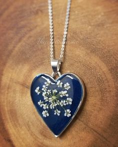 a blue heart shaped pendant with white flowers on it