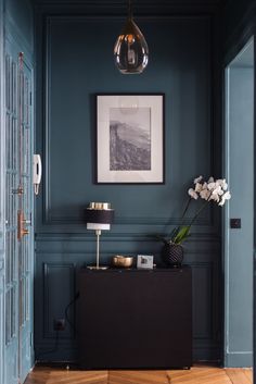 a room with blue walls and white flowers on the table in front of an open door