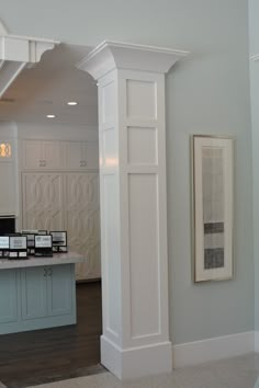 an empty kitchen with white cabinets and marble counter tops, along with framed pictures on the wall