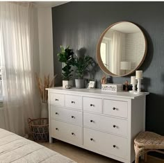 a white dresser sitting next to a window with a mirror on it's side