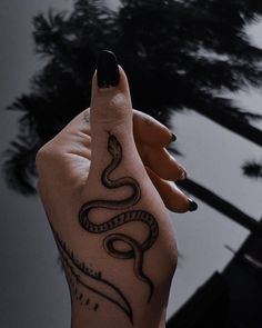 a woman's hand with a snake tattoo on it