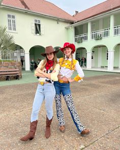 two women in cowboy hats and jeans posing for the camera with their arms around each other