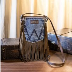 a purse with fringes on it sitting next to two suitcases and a box