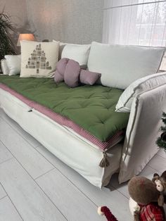 a living room with a couch and pillows on the floor next to a christmas tree