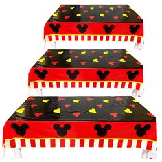 three mickey mouse themed tables with red and yellow tablecloths on them, all decorated in different shapes and sizes