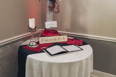 a table topped with a vase filled with flowers next to a white table cloth covered table