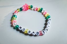 a beaded bracelet with words written in different colors and shapes, on a white surface