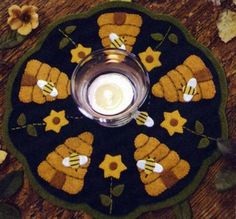 a candle is sitting on top of a black and yellow flowered doily with flowers around it