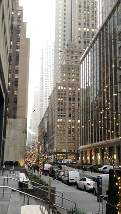 a city street filled with lots of tall buildings next to parked cars and traffic lights