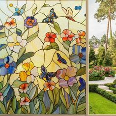 a stained glass window with flowers and butterflies in the center is next to a garden