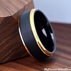 a black and gold ring sitting on top of a wooden block