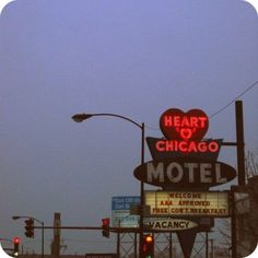 the heart of chicago motel sign is lit up at night with street lights and traffic signals