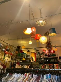 a room filled with lots of different types of shirts and lamps hanging from the ceiling