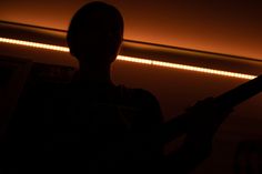 the silhouette of a person holding a baseball bat in front of a wall with lights