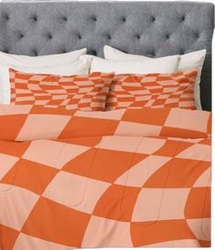 an orange and white checkered comforter set on a bed with two pillow cases