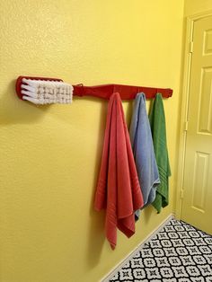 three colorful towels hanging on a wall next to a toothbrush and towel rack in a bathroom