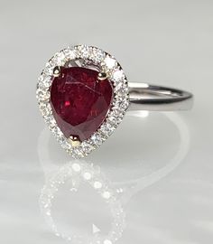 Ruby Engagement Ring, Ruby Engagement Ring White Gold, Pear Shaped Ruby Ring, Pear Shaped Ruby Engagement Ring, 2 Carat Ruby Ring, Ruby Ring A classic and mesmerizing genuine ruby ring featuring a lustrous pear shaped center stone weighing 2.22 carats surrounded by a traditional halo of sparkling white diamonds weighing 0.66 carats. *Approximate ring weight: 3.33 grams *Ring size: 7 * Complimentary resizing is available up to 3 sizes larger or smaller than stated size. Gia Certified Teardrop Ring For Anniversary, Gia Certified Pear-shaped Ring For Anniversary, Gia Certified Teardrop Wedding Rings, Silver Pear-shaped Ring With Halo Setting, Gia Certified Pear-shaped Anniversary Rings, Pear-shaped Gia Certified Rings For Anniversary, Fine Jewelry Teardrop Anniversary Rings, Fine Jewelry Teardrop Ring For Anniversary, Gia Certified Teardrop Diamond Ring Fine Jewelry