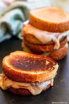 two grilled cheese sandwiches sitting on top of a black table next to each other