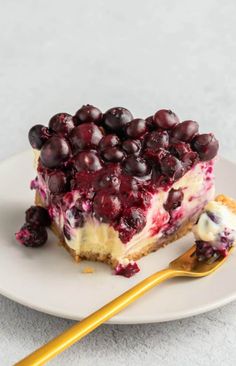 a piece of cheesecake with blueberries and whipped cream on a plate next to a fork