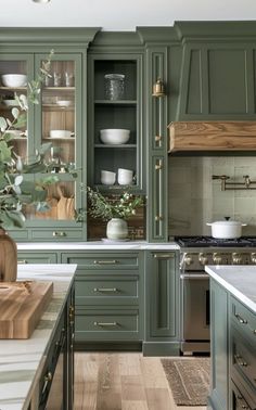 a kitchen with green cabinets and white counter tops in the center, along with a wooden cutting board