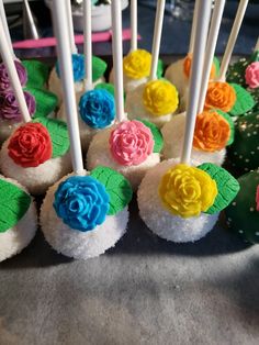 there are many cupcakes with colorful frosting on the top and flowers on the bottom