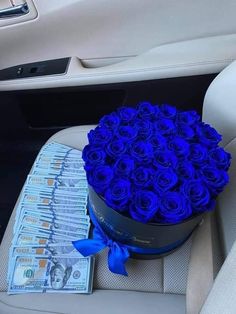 a bouquet of blue roses sitting on top of a car seat next to a pile of money