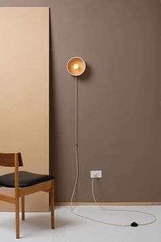 a wooden chair sitting next to a wall with a light on it's side