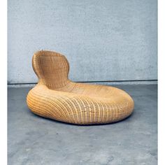 a wicker chair sitting on top of a cement floor next to a concrete wall