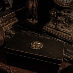 an antique black box sitting on top of a table next to a statue and clock