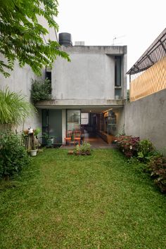 an outdoor area with green grass and plants in front of a concrete building on the corner