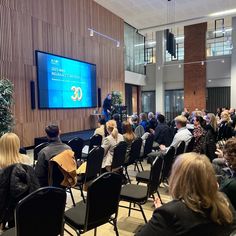 a group of people are sitting in chairs and watching a presentation on a large screen