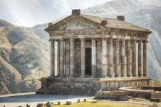 an old building with columns in front of mountains