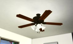 a ceiling fan with three wooden blades in a room