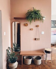 a wooden bench sitting under a mirror next to two baskets filled with plants and potted plants