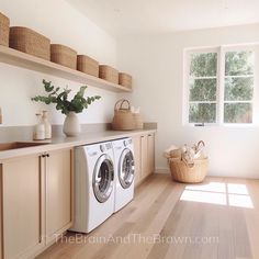 a washer and dryer sitting in a room next to some shelves with baskets on them