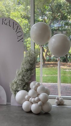 balloons and greenery are on display in front of a window