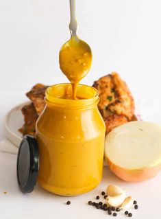 a spoon is pouring mustard into a jar