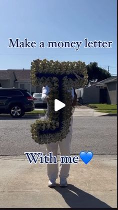 a man standing on the sidewalk holding up a letter that says make a money letter with me